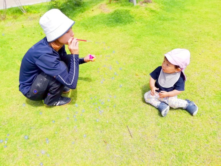 三宮の芝生でシャボン玉をする保育士と園児