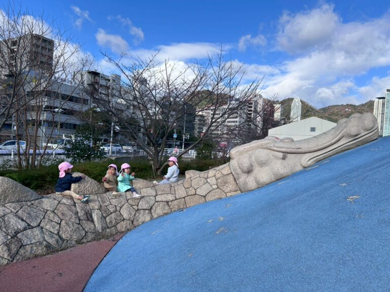 神戸三宮エリアにある水色の坂と滑り台がある公園で遊ぶ園児たち