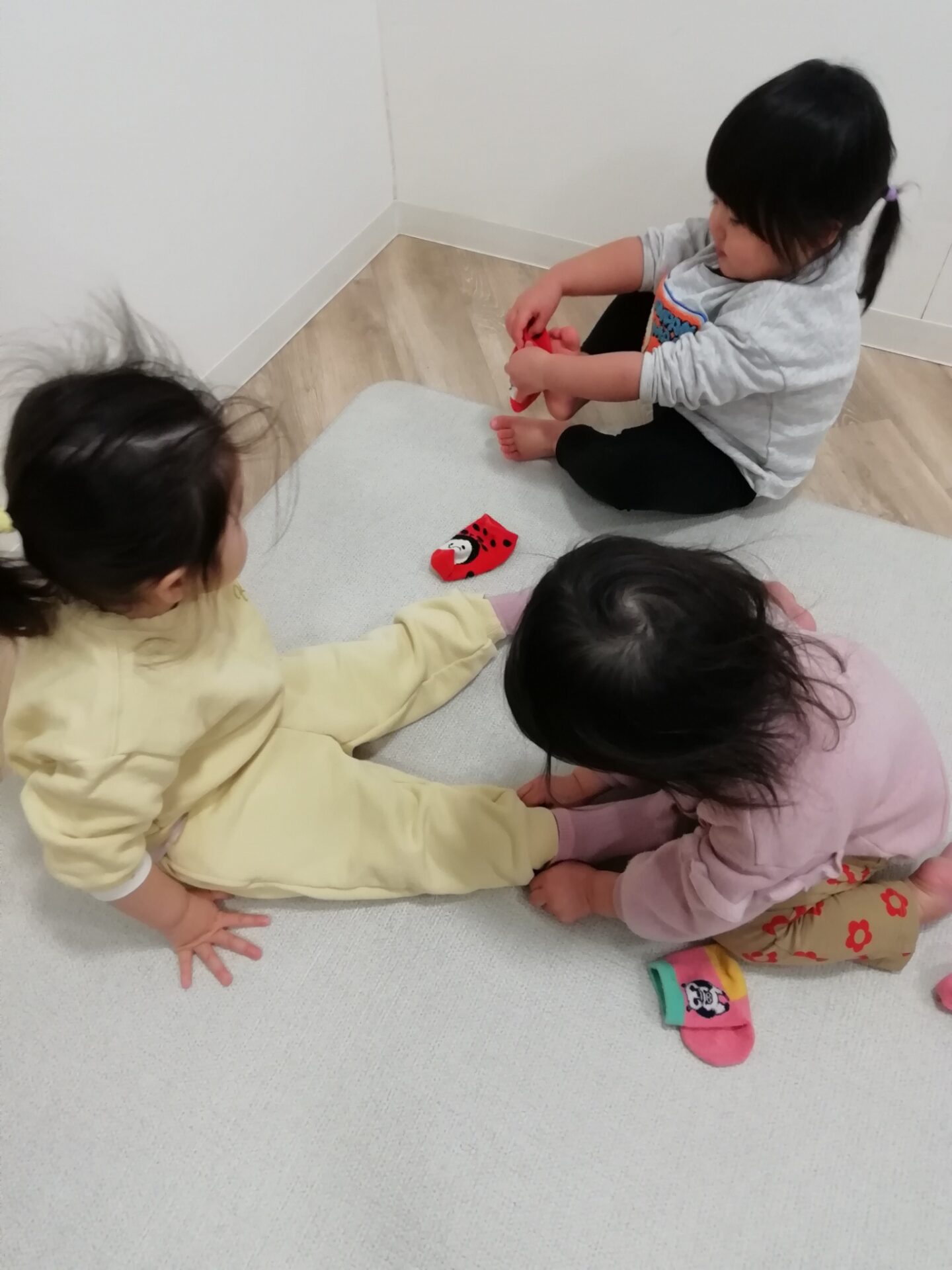 靴下を履くお手伝いをする園児たち