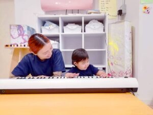 三宮園でピアノ遊びを楽しむ保育士と園児