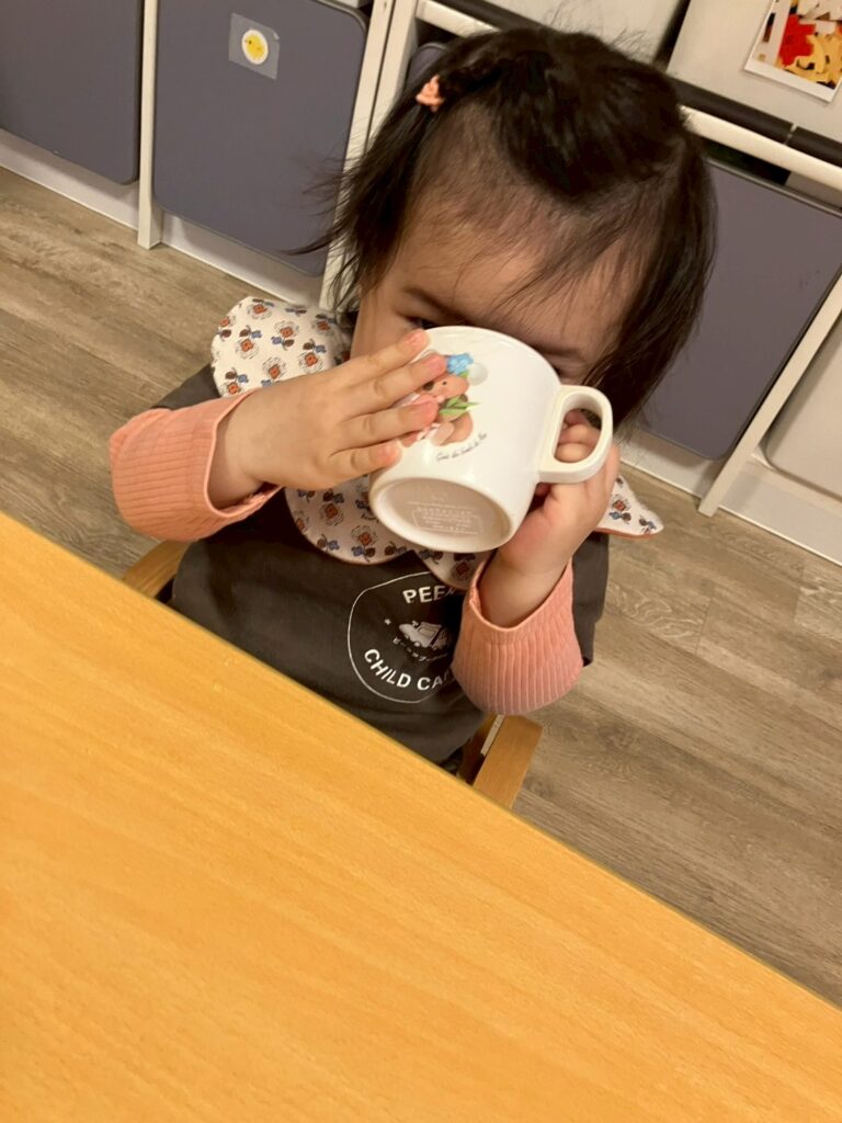 朝のおやつ時に飲み物を飲む園児
