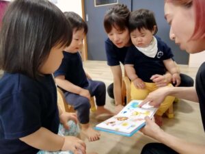 英語の絵本をみんなで読む園児と保育士