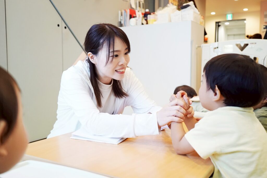 朝の会で歌を歌う保育士と園児たち