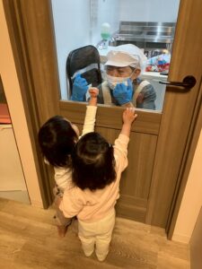 扉越しでコミュニケーションをとる調理員さんと園児たち