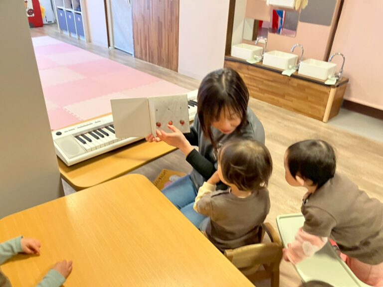 保育士が読む絵本に興味深々の園児たち