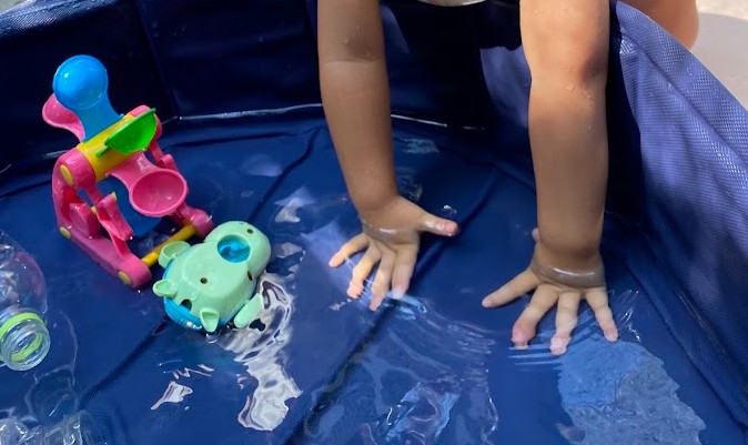たくさんのおもちゃで水遊びをする1歳児