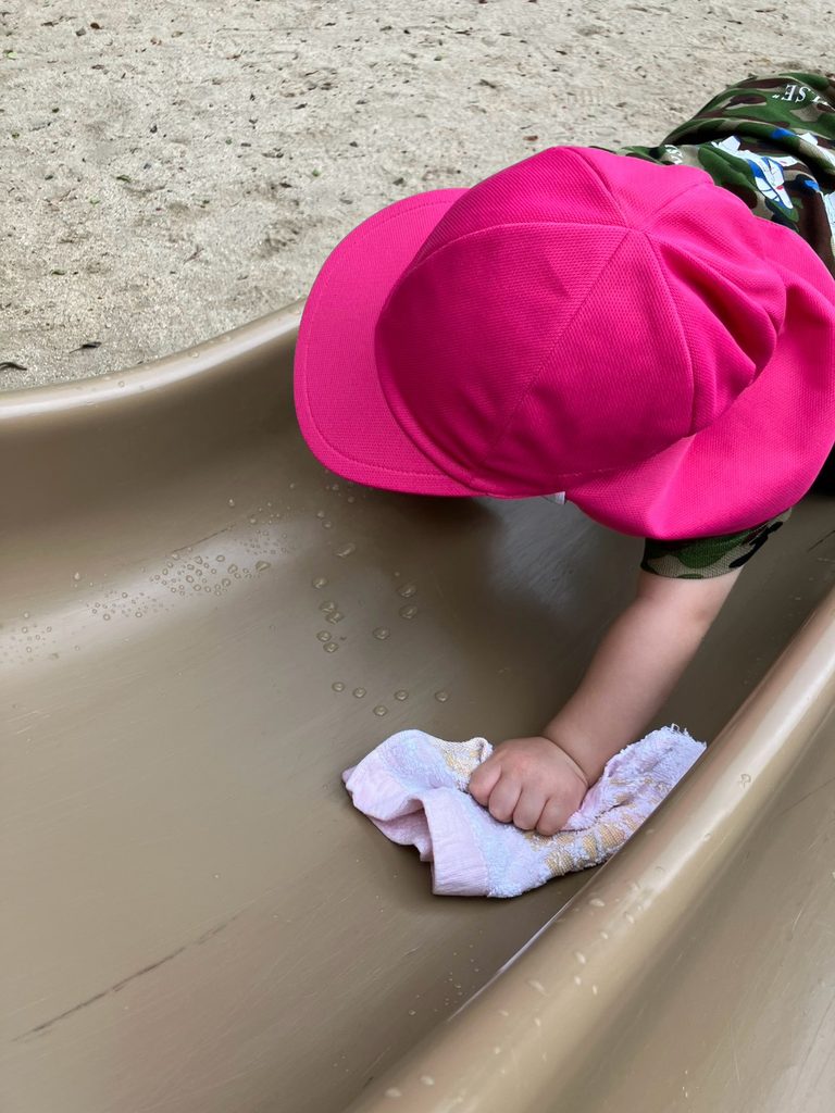 南堀江にある高台橋公園の滑り台の水滴を一生懸命拭く1歳のPEEK A BOO保育園 南堀江の園児